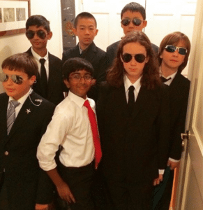 Kids in suits with brown kid Protecting meme template