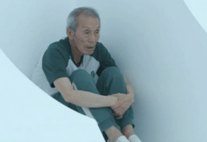 Old man from Squid Game sitting down Il-nam meme template